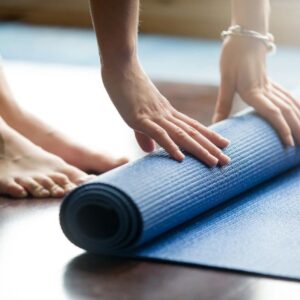 Person preparing to do yoga by unrolling a blue yoga mat.