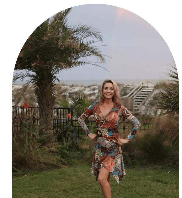 Woman in a floral dress posing outdoors by a palm tree.