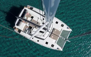 Aerial view of a white catamaran sailing on clear turquoise waters.
